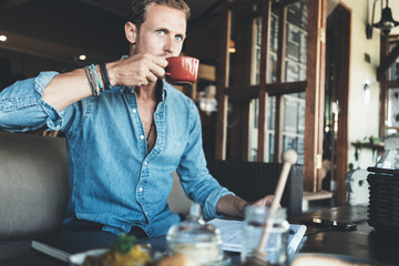 Wall Mural - Young entrepreneur working on business project in city cafe, drinking coffee