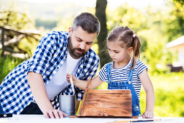 Wall Mural - Father with a small daughter outside, making wooden birdhouse.