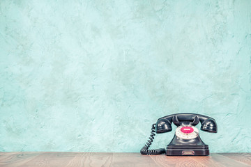 Fototapete - Retro classic outdated black rotary telephone on wooden table front textured aquamarine concrete wall background. Vintage instagram old style filtered photo