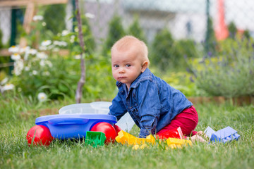 Wall Mural - Little baby boy, playing with big construction blocks in garden