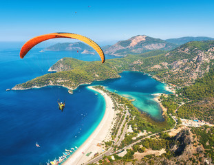 Canvas Print - Paragliding in the sky. Paraglider tandem flying over the sea with blue water and mountains in bright sunny day. Aerial view of paraglider and Blue Lagoon in Oludeniz, Turkey. Extreme sport. Landscape