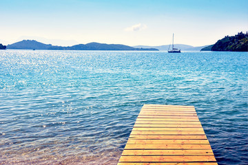 Wall Mural - beautiful scenic landscape with a boat in the bay and a wooden pier near nydri, lefkada, greece. stu
