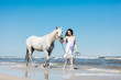 © Photocreo Bednarek - Girl walking on the beach with white horse.