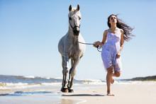 Young Woman Witth White Horse Running On The Beach