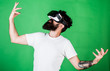 © be free - Hipster on enthusiastic face having fun in virtual reality. Virtual party concept. Guy with head mounted display dance in virtual reality. Man with beard in VR glasses dancing, green background