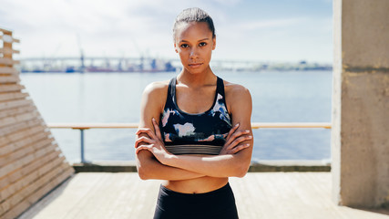 Wall Mural - Portrait of a serious sports woman standing outdoors with  arms crossed