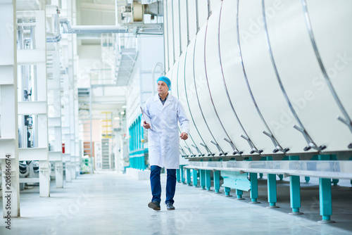 Fotografía Full length portrait of senior factory worker walking towards camera crossing wo