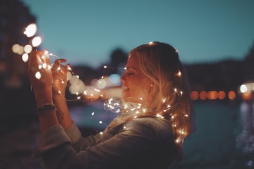 Blonde woman playing with garland fairy lights