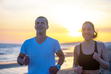 Man and women running on tropical beach at sunset