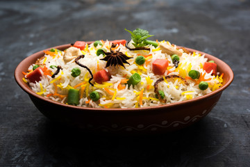 Indian Vegetable Pulav or Biryani made using Basmati Rice, served in a ceramic bowl. selective focus