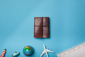 Wall Mural - Leather journal on minimal blue background with plane and other items