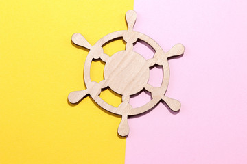 Marine attributes. Wooden steering wheel On a bright pink and yellow background. Top view.
