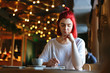 © Comeback Images - Portrait of young woman with red hair studying or working in cafe. Creative girl sitting at table and writing in her notebook