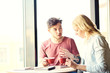 © Comeback Images - Young man talking something to his girlfriend who texting on her smartphone. Couple having coffee together in cafe