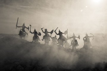 Wall Mural - Medieval battle scene with cavalry and infantry. Silhouettes of figures as separate objects, fight between warriors on sunset foggy background.