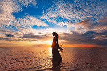 Elegant Woman Dancing On Water. Sunset And Silhouette