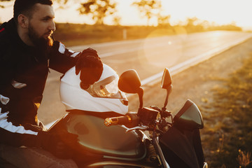 Wall Mural - Close up portrait of a handsome bearded man resting near the road while traveling on his motorcycle around Europe.