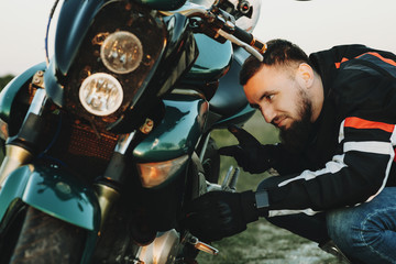 Wall Mural - Bearded caucasian traveler searching the problem on his motorcycle while traveling in his adventure time.