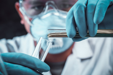 scientist dropping chemical liquid to flask with lab glassware background, Laboratory research concept,Researcher is dropping the reagent into test tube.