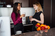 © undrey - Two girlfriends in elegant clothes relaxing after shopping, drinking wine, laughing and gossiping in the kitchen