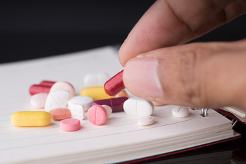 Wall Mural - Man's hand holding a medical pills with a lot of pills and capsules in the background.