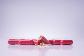 Wall Mural - Red medical pills or capsules on white table with reflection.Red medical pills isolated over white background.