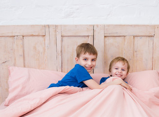 Little brothers playing in bed. Kids playing in a modern bedroom before sleeptime.