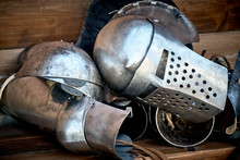 Closeup Of A Knight's Armor, Helmet, Glove And Part Of The Trunk Lie On A Wooden Bench After A Tournament Or Battle. The Concept Of Disarmament And Peace.