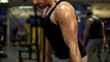 © motortion - Guy working hard in gym doing brisk pull-downs with one arm, finishing exercise