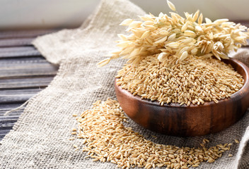 Ears of oats and oatmeal in bowl on table. Uncooked porridge