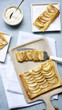 © The Picture Pantry - A rectangular apple tart on a wooden serving board cut in pieces being served onto dessert plates.