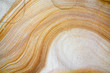 Close-up of natural sandstone texture with yellow and white layered wave pattern