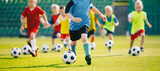 Fototapeta Sport - Football soccer training for kids. Children football training session. Kids running and kicking soccer balls. Young boys improving soccer skills