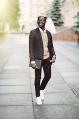 Full length portrait of young african businessman walking in the city street