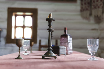 Retro Candelabra With Candles In old Room Interior, wooden house, vintage glass and metal beaker on a table