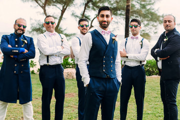 Wall Mural - Handsome Indian groom and groomsmen in classy suits pose together on the lawn