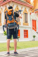 Tourist with backpack standing during a travel in Thailand in asia and holding a stabilizer gimbal with smart phone. Digital nomad backpacker concept