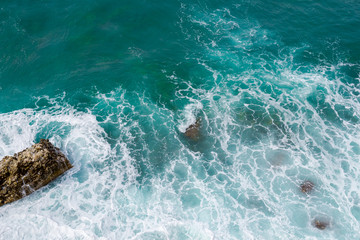 Wall Mural - Big waves breaking on the shore. Waves and white foam. Coastal stones. View from above. The marine background is green