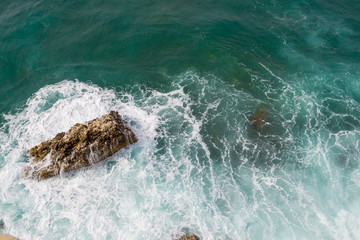 Wall Mural - Big waves breaking on the shore. Waves and white foam. Coastal stones. View from above. The marine background is green