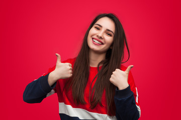 Cheerful trendy girl holding thumbs up