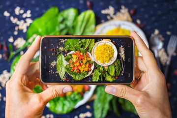 Wall Mural - Smartphone photography of food. Woman hands take phone photography of fresh vegetables salad and Arabian bulgur for lunch or dinner. Good for social media publications or blogging.