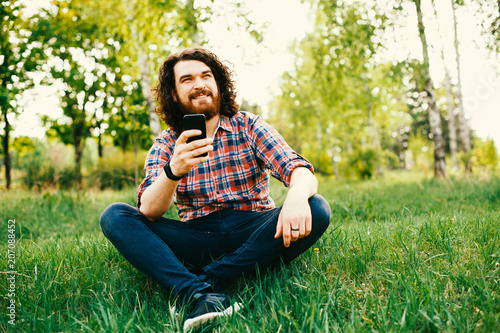 Happy Bearded Hipster Man With Long Curly Hair Sitting Ouside And