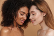 © Drobot Dean - Beauty portrait closeup of two different nation smiling women, african american and caucasian girls with closed eyes, posing face to face isolated over beige background