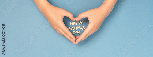 Happy Father's day banner with childs hands in shape of heart and wooden lett...