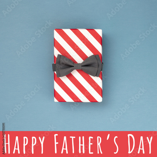 One gift box wrapped in red striped paper and tied with the grey bow tie on b...
