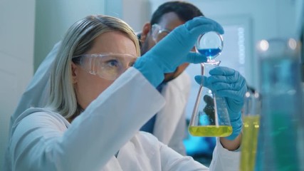 Wall Mural - life scientists working at a laboratory. young life scientists performing a colourful chemical exper