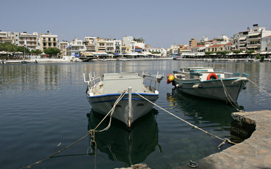 The white boats on the coast of the lake and white houses and cafes in the small mediterranean town on the sunny day