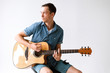 © alexbutko_com - Handsome and cheerful guy musician in a shirt playing guitar