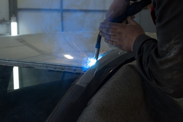 Wall Mural - Experienced man performs work on body repair car with a welding machine. Repair of the roof of the vehicle.