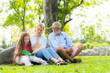 © Soonthorn - Grandfather and grandmother of the elder family reading a book with granddaughter in the park.